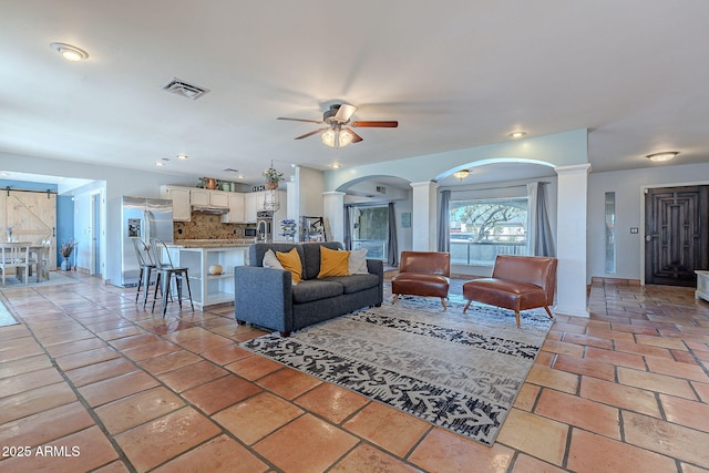 living room featuring ceiling fan and decorative columns