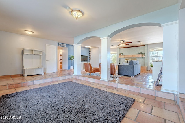 interior space with ceiling fan and decorative columns