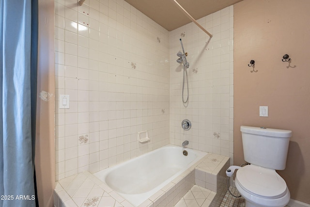 bathroom featuring tiled shower / bath combo and toilet