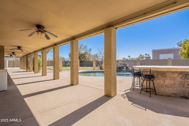 view of patio / terrace featuring a bar, pool water feature, a fenced in pool, and ceiling fan