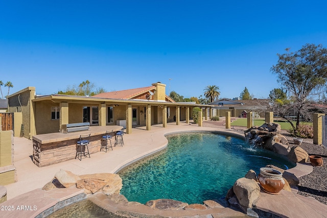 view of swimming pool with a patio, an outdoor bar, and pool water feature