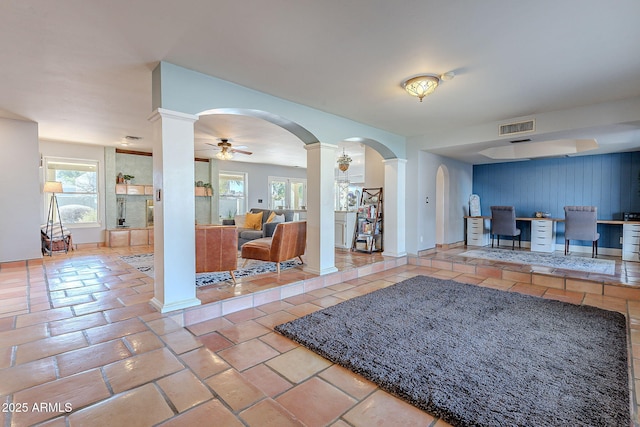 interior space with decorative columns, plenty of natural light, and ceiling fan