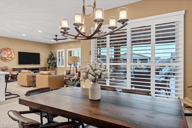 dining space with ceiling fan with notable chandelier and light hardwood / wood-style floors