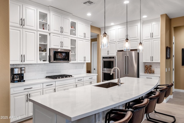 kitchen featuring white cabinetry, appliances with stainless steel finishes, a kitchen island with sink, and a breakfast bar