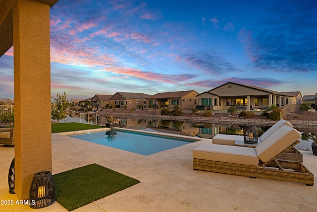 pool at dusk with a water view and a patio