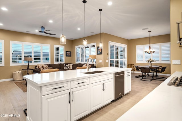 kitchen featuring light hardwood / wood-style floors, sink, hanging light fixtures, and white cabinets