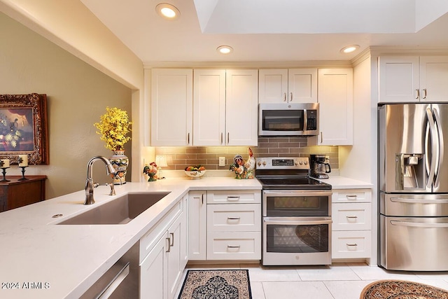 kitchen with tasteful backsplash, white cabinetry, sink, and stainless steel appliances