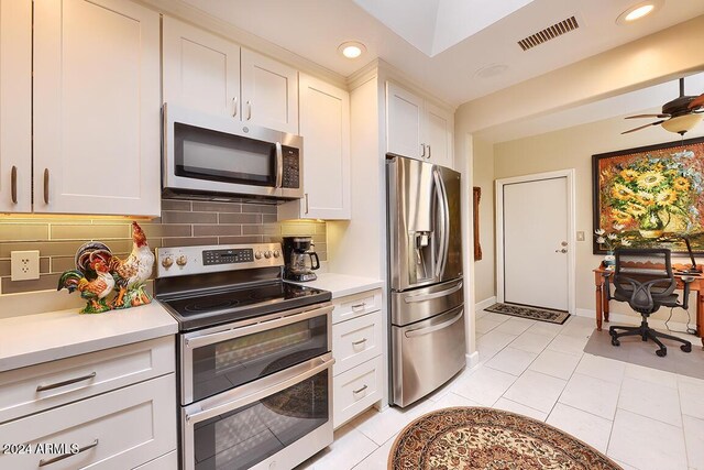 kitchen with decorative backsplash, appliances with stainless steel finishes, ceiling fan, white cabinets, and light tile patterned flooring