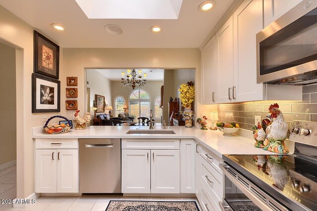 kitchen with decorative backsplash, stainless steel appliances, light tile patterned floors, an inviting chandelier, and white cabinets