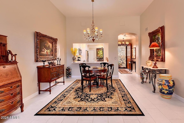 dining space featuring light tile patterned floors, a high ceiling, and an inviting chandelier