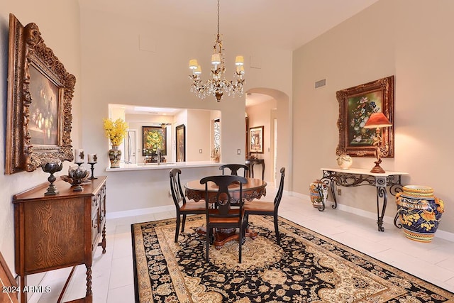 dining room featuring light tile patterned floors, a notable chandelier, and a high ceiling