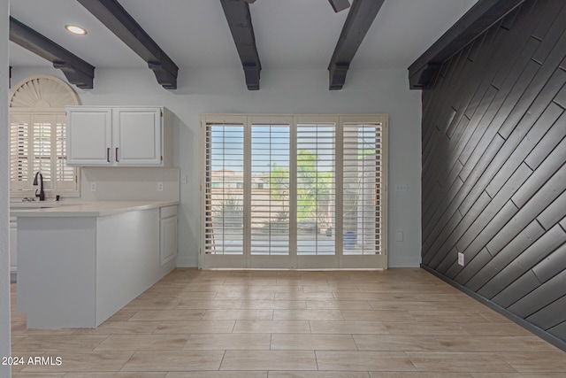 interior space featuring light wood-type flooring, wooden walls, sink, and beamed ceiling