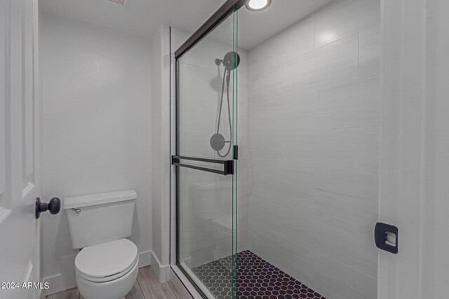 bathroom with walk in shower, toilet, and wood-type flooring