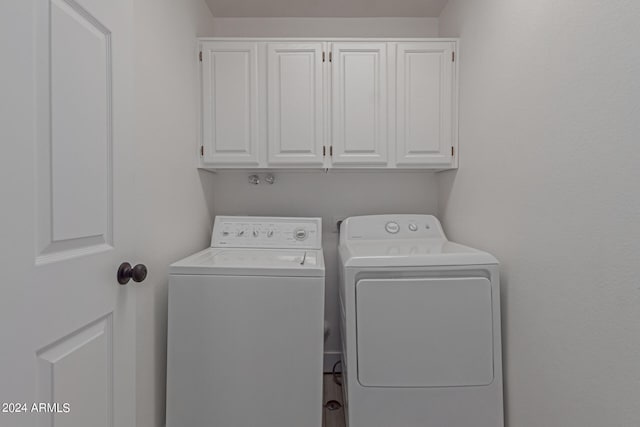 clothes washing area featuring cabinets and washing machine and dryer