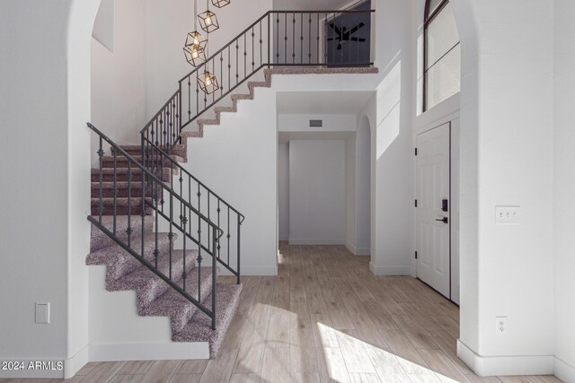 entryway featuring light hardwood / wood-style flooring and a towering ceiling