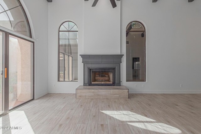 unfurnished living room featuring light hardwood / wood-style floors, a towering ceiling, and ceiling fan