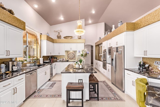 kitchen with a kitchen bar, a center island, stainless steel appliances, and high vaulted ceiling