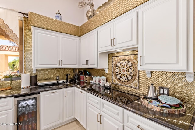 kitchen featuring decorative backsplash, white cabinetry, beverage cooler, and dark stone counters