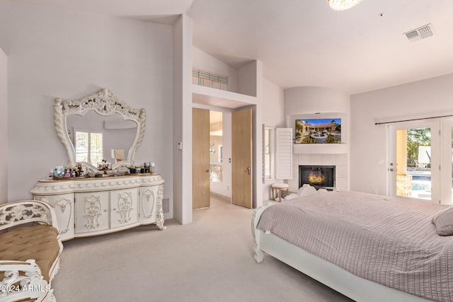 bedroom with a tile fireplace, light colored carpet, vaulted ceiling, and multiple windows