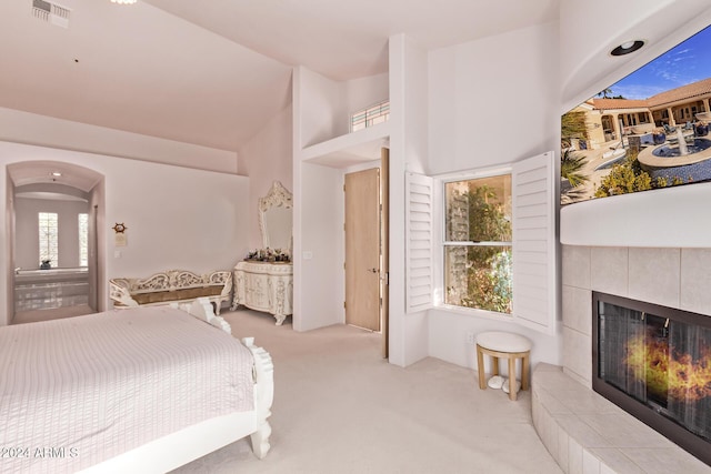 bedroom with multiple windows, light colored carpet, and a tile fireplace