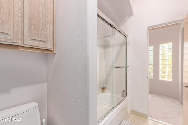 bathroom featuring enclosed tub / shower combo and toilet