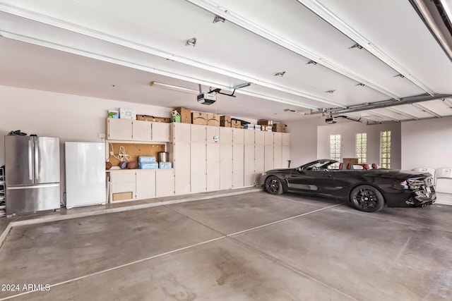 garage with white fridge, a garage door opener, and stainless steel refrigerator