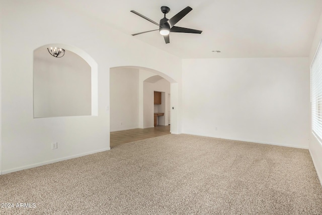 spare room with visible vents, carpet floors, lofted ceiling, and ceiling fan with notable chandelier