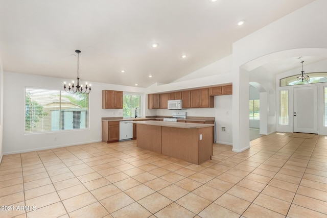 kitchen featuring white appliances, a kitchen island, an inviting chandelier, hanging light fixtures, and light countertops