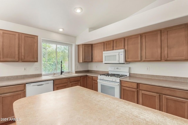 kitchen with light countertops, recessed lighting, brown cabinetry, white appliances, and a sink