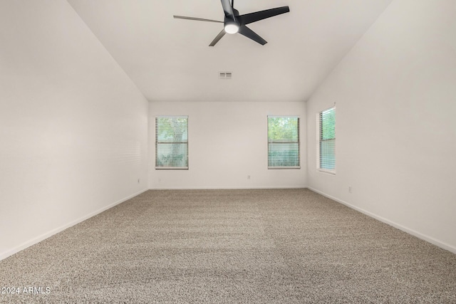 carpeted spare room featuring a wealth of natural light, visible vents, a ceiling fan, and vaulted ceiling