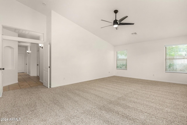 carpeted spare room featuring a ceiling fan, visible vents, a wealth of natural light, and high vaulted ceiling