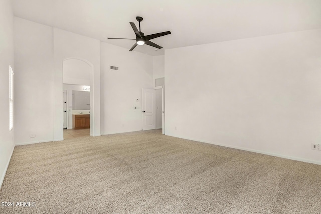 spare room featuring visible vents, ceiling fan, light colored carpet, arched walkways, and high vaulted ceiling