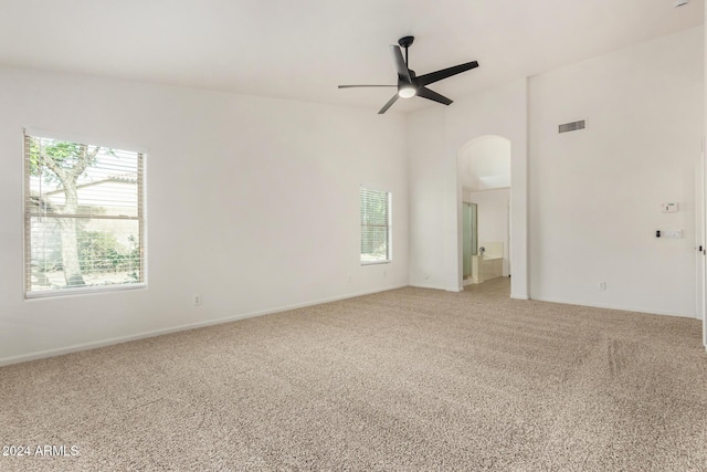 spare room featuring visible vents, light carpet, arched walkways, and ceiling fan