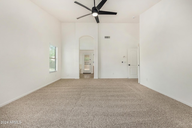 unfurnished room with visible vents, a ceiling fan, a high ceiling, baseboards, and light colored carpet