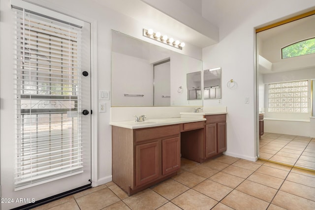 bathroom with double vanity, baseboards, tile patterned floors, and a sink