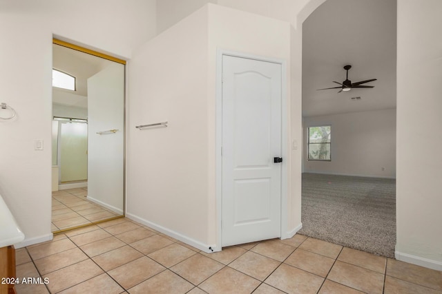 hallway with light tile patterned floors, baseboards, arched walkways, and light carpet