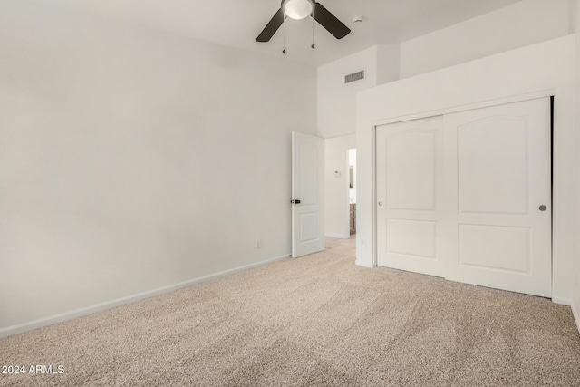 unfurnished bedroom featuring visible vents, a ceiling fan, a closet, baseboards, and light colored carpet