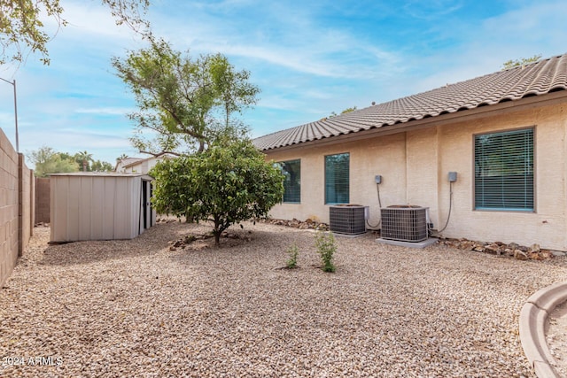 exterior space with stucco siding, cooling unit, a storage unit, and an outdoor structure