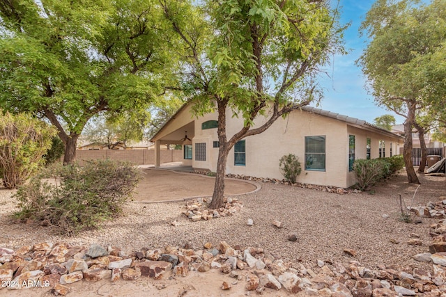 view of property exterior featuring a patio area, stucco siding, a tile roof, and fence