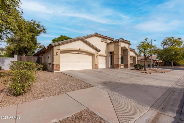 mediterranean / spanish house with fence, stucco siding, concrete driveway, a garage, and stone siding