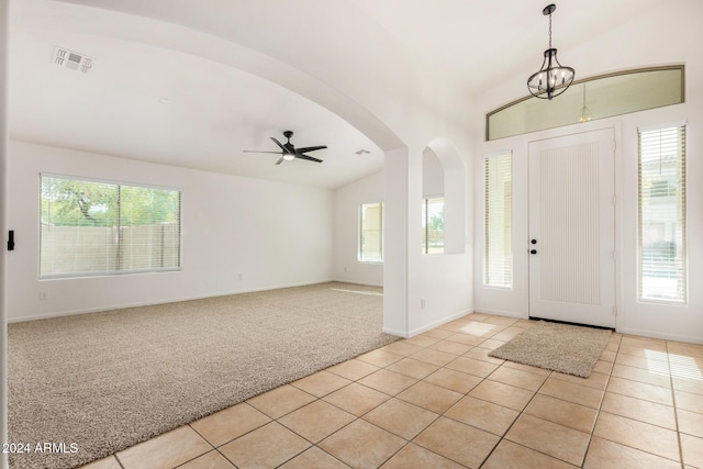 entryway with a healthy amount of sunlight, lofted ceiling, light carpet, light tile patterned floors, and arched walkways