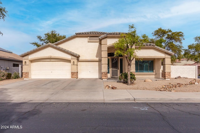 mediterranean / spanish-style home featuring an attached garage, stone siding, driveway, and stucco siding