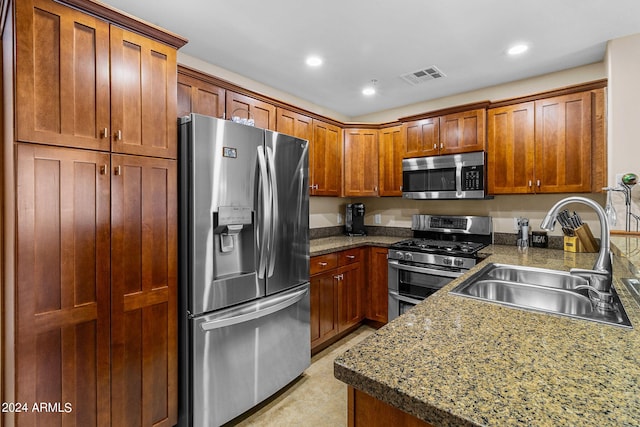 kitchen with dark stone countertops, appliances with stainless steel finishes, and sink