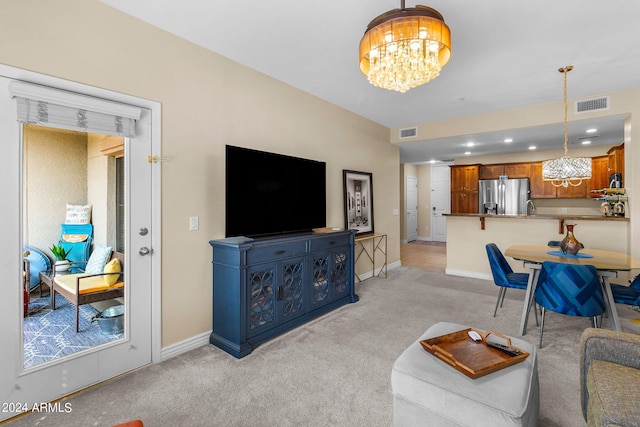 living room featuring sink, a chandelier, and light colored carpet