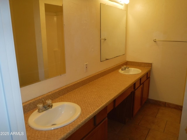 full bath featuring a sink, baseboards, double vanity, and tile patterned floors