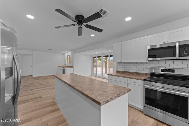 kitchen featuring white cabinets, a kitchen island, light wood-type flooring, and appliances with stainless steel finishes