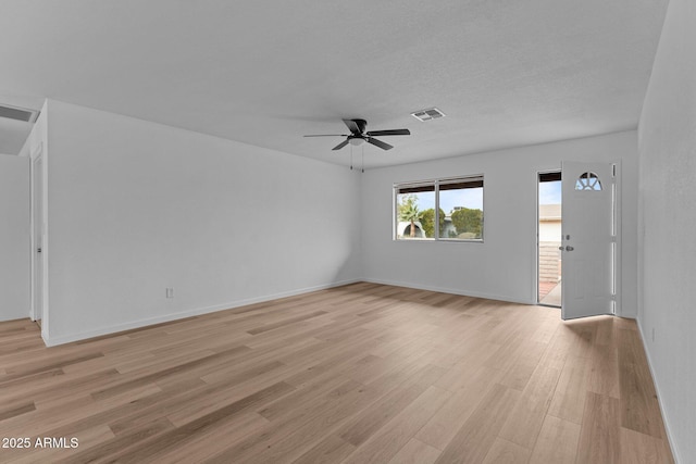 spare room with a textured ceiling, light wood-type flooring, and ceiling fan