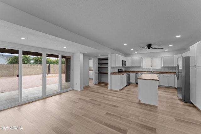 kitchen with sink, a center island, wooden counters, white cabinets, and appliances with stainless steel finishes