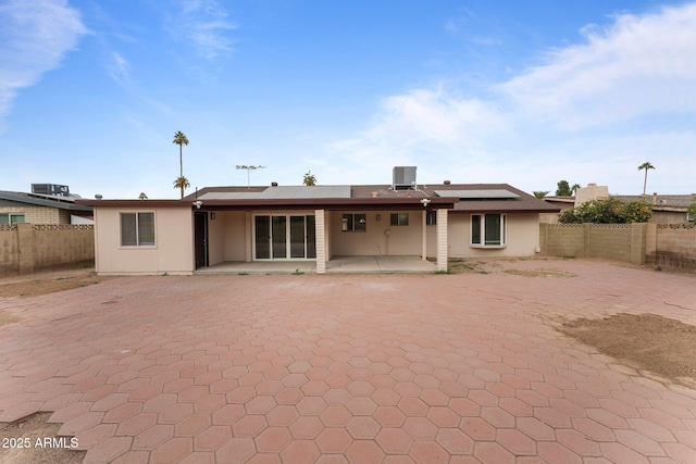 back of property featuring solar panels, cooling unit, and a patio