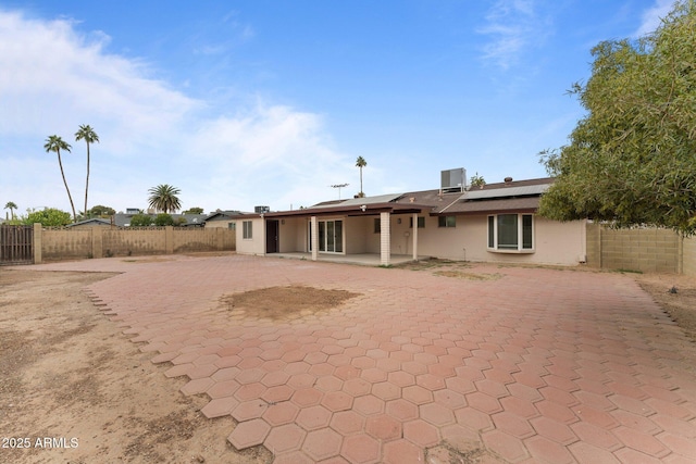 back of property with solar panels, cooling unit, and a patio area